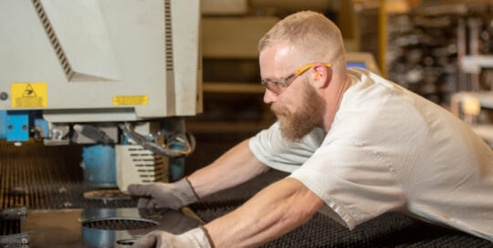 worker running a punch press machine